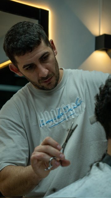 Nahuel, barbero de Lorenzo's Barber Studio, trabajando con tijera